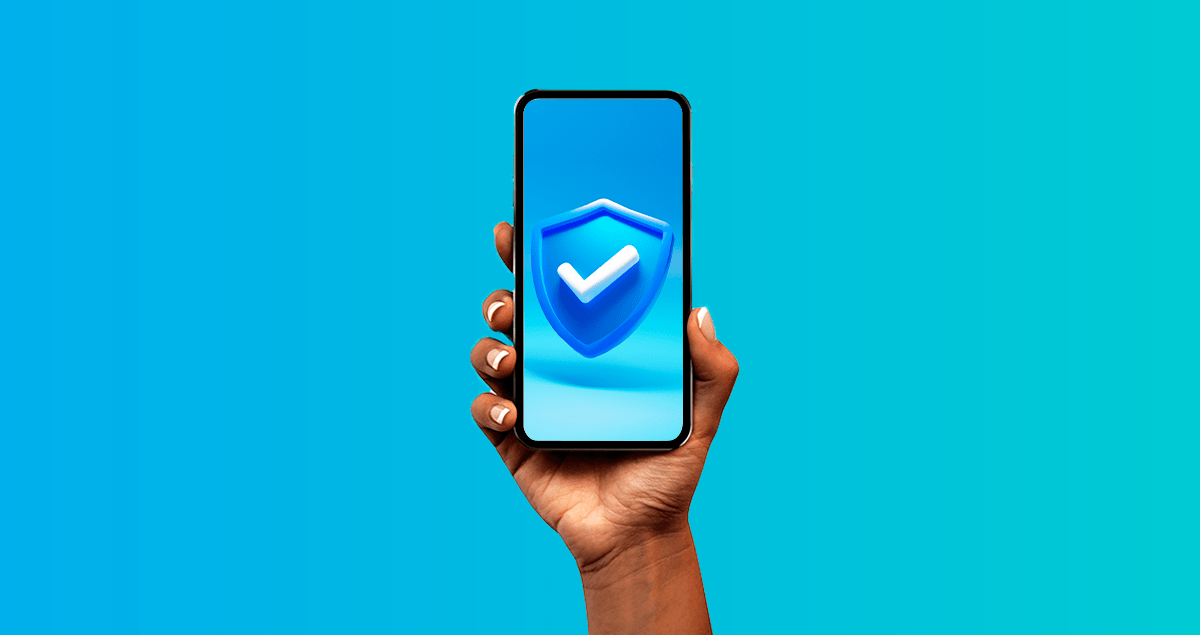 Mão segurando celular com símbolo de segurança na tela