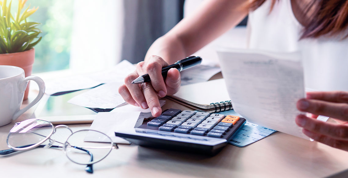 Mulher usando calculadora e segurando papel