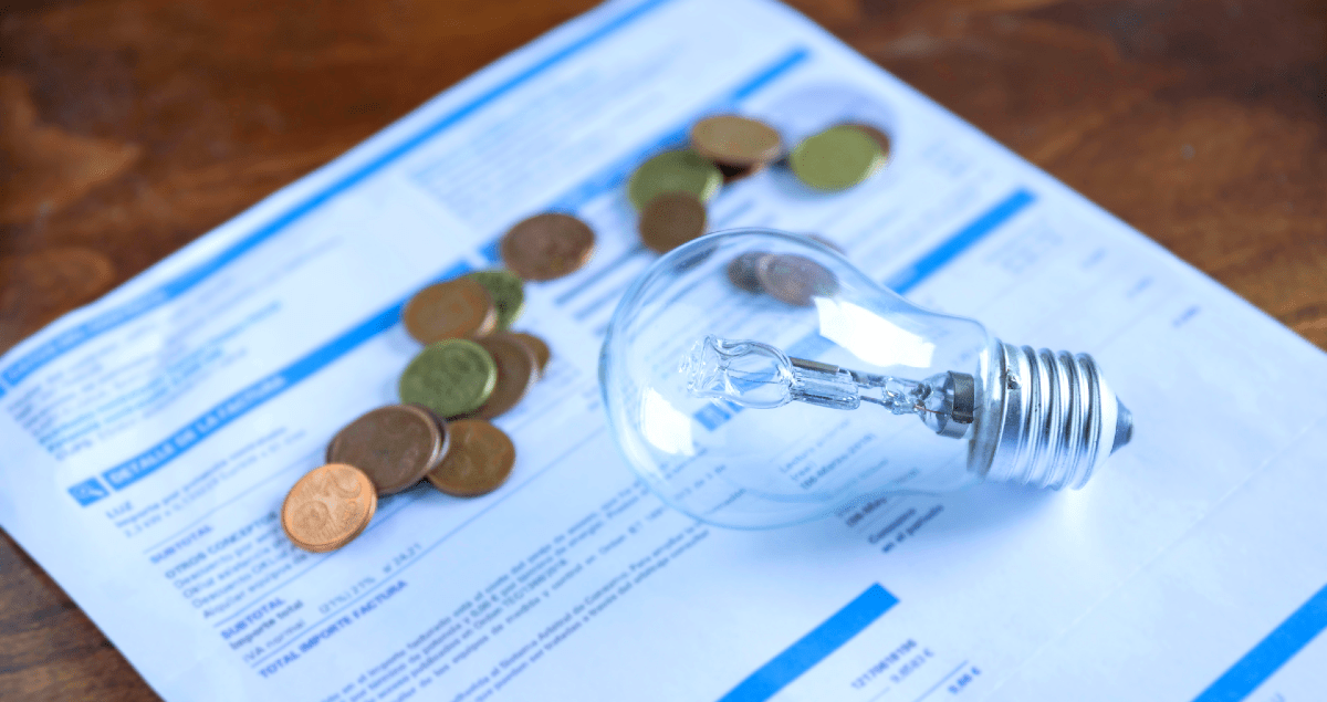 Lâmpada sobre conta de luz com moedas ao redor
