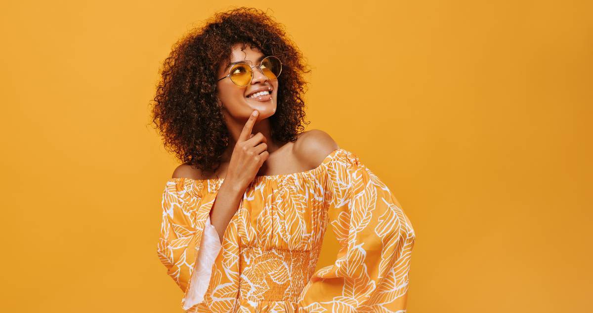 Mulher sorrindo em frente a fundo laranja