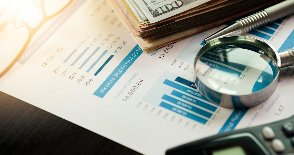 Papel com relatórios, lupa, calculadora e notas de dólar