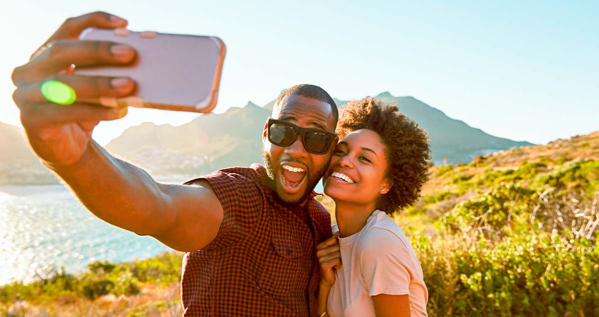 Homem e mulher tirando selfie à beira do mar