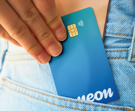 Mão retirando o cartão Neon do bolso de uma calça jeans